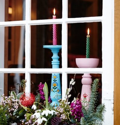 Bild av harmoniska ljusstakar och blommor i fönster