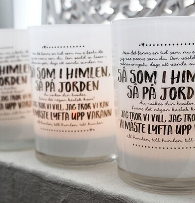 Bild av stilrena ljuslyktor i frostat glas med texter