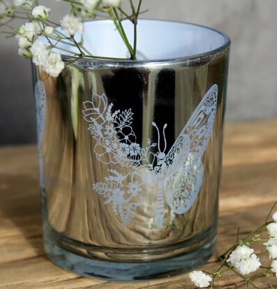 Bild av ljuslykta med fjärilsmotiv på rustikt bord