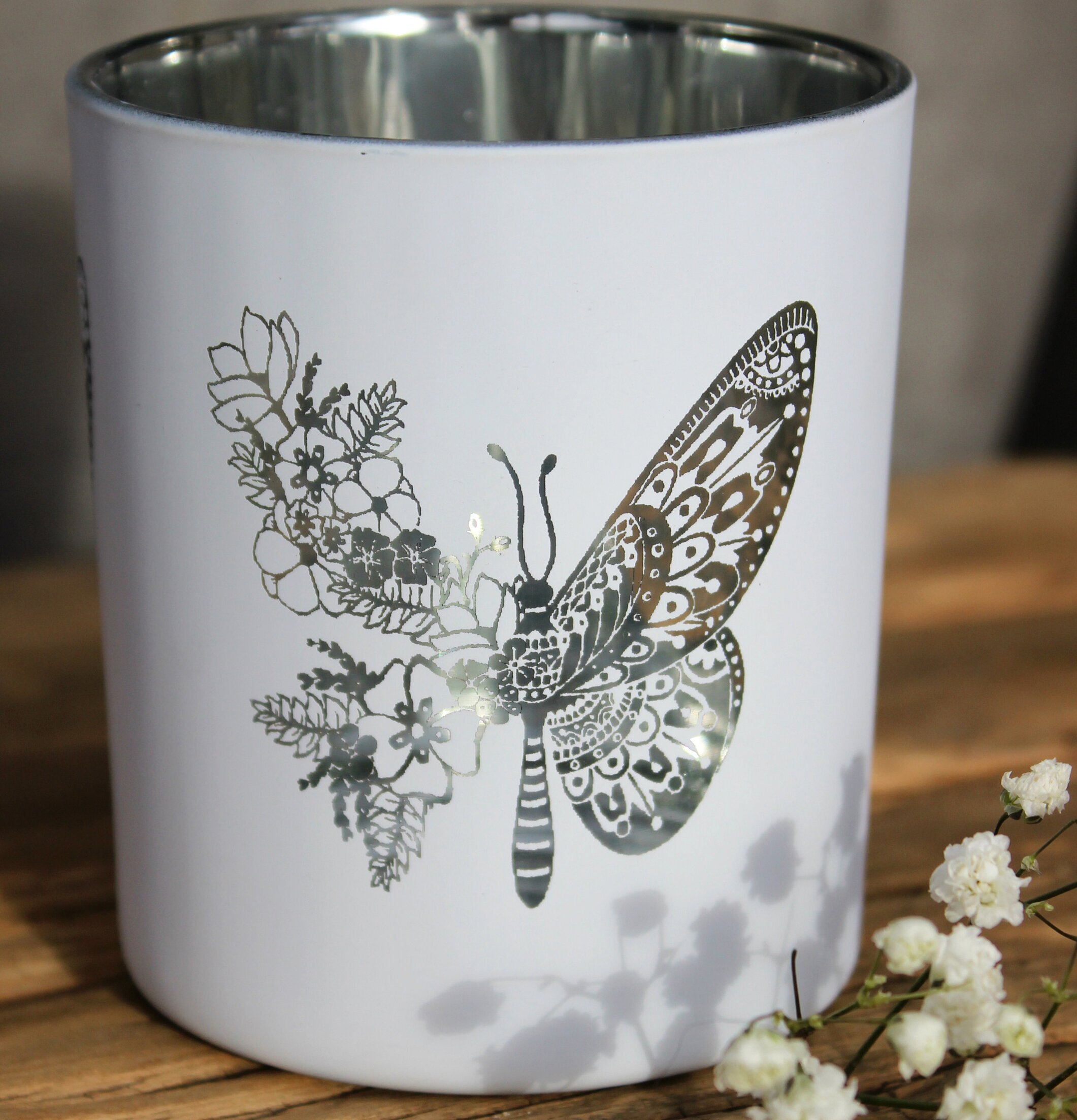 Bild av stilren ljuslykta med fjärilar och blommor