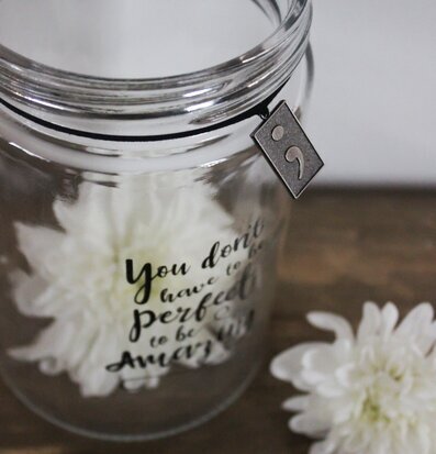 Bild av glaslykta med inspirerande text och dekorativ berlock