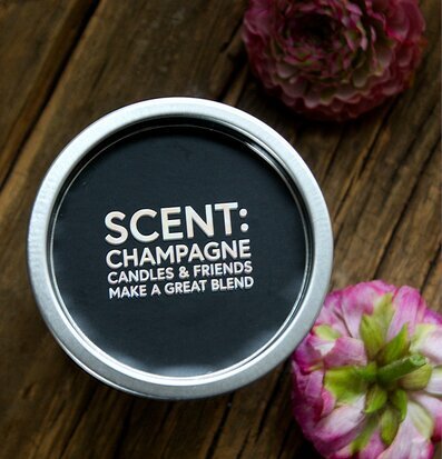 Bild av doftljus i silverburk med blommor i bakgrunden