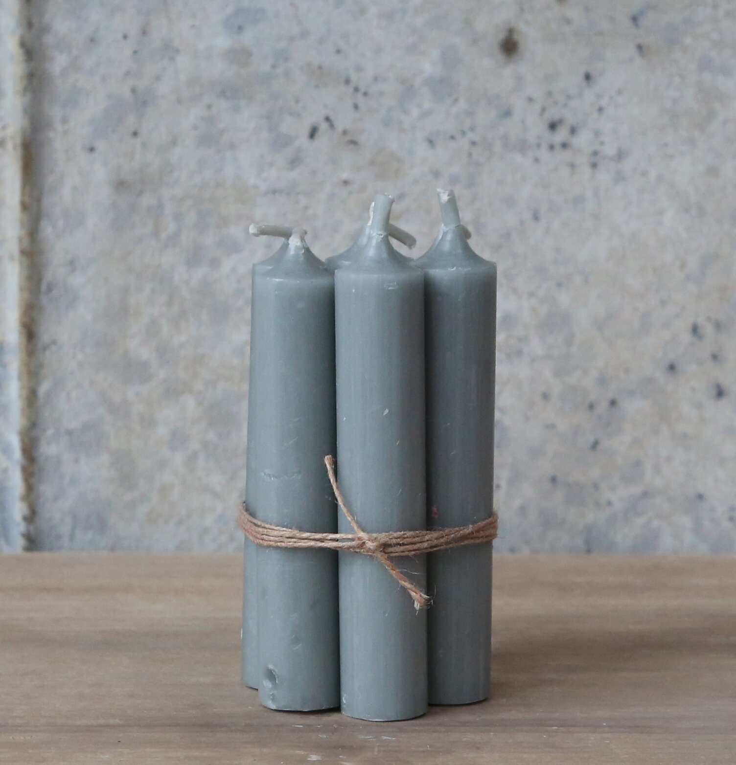 Bild av grå stearinljus med rustikt snöre och träbakgrund