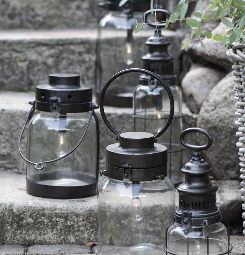 Bild av ljuslyktor i metall på stenlagd trappa