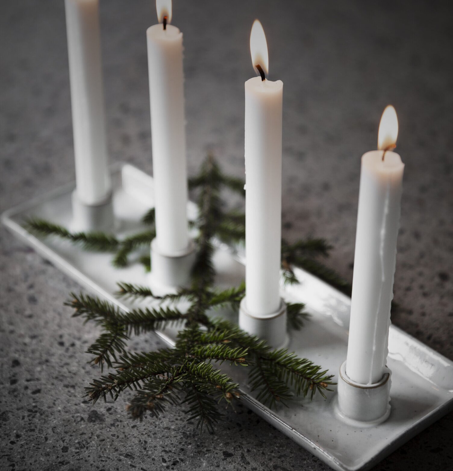 Foto av stilren ljusstake med fyra ljus och grankvistar