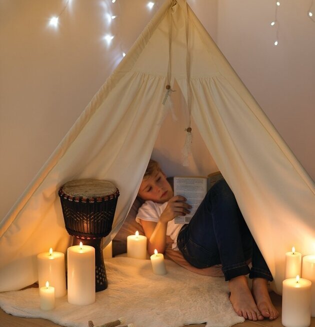 Bild av mysigt tält med LED-ljus och läsande barn