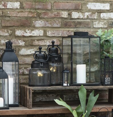 Bild av ljuslyktor mot rustik tegelvägg och träplattform