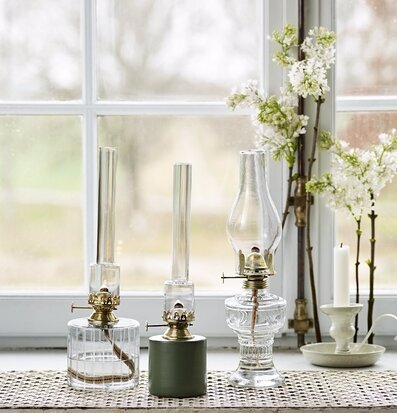 Bild av fotogenlampor i fönster med grönskande bakgrund