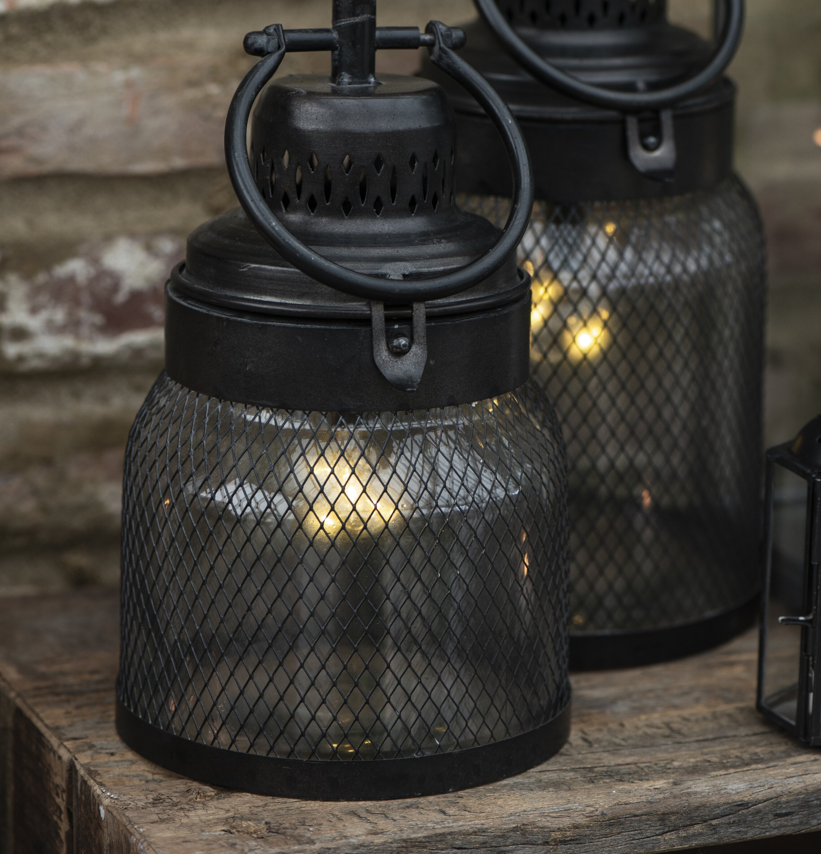 Bild av två identiska ljuslyktor på rustik yta