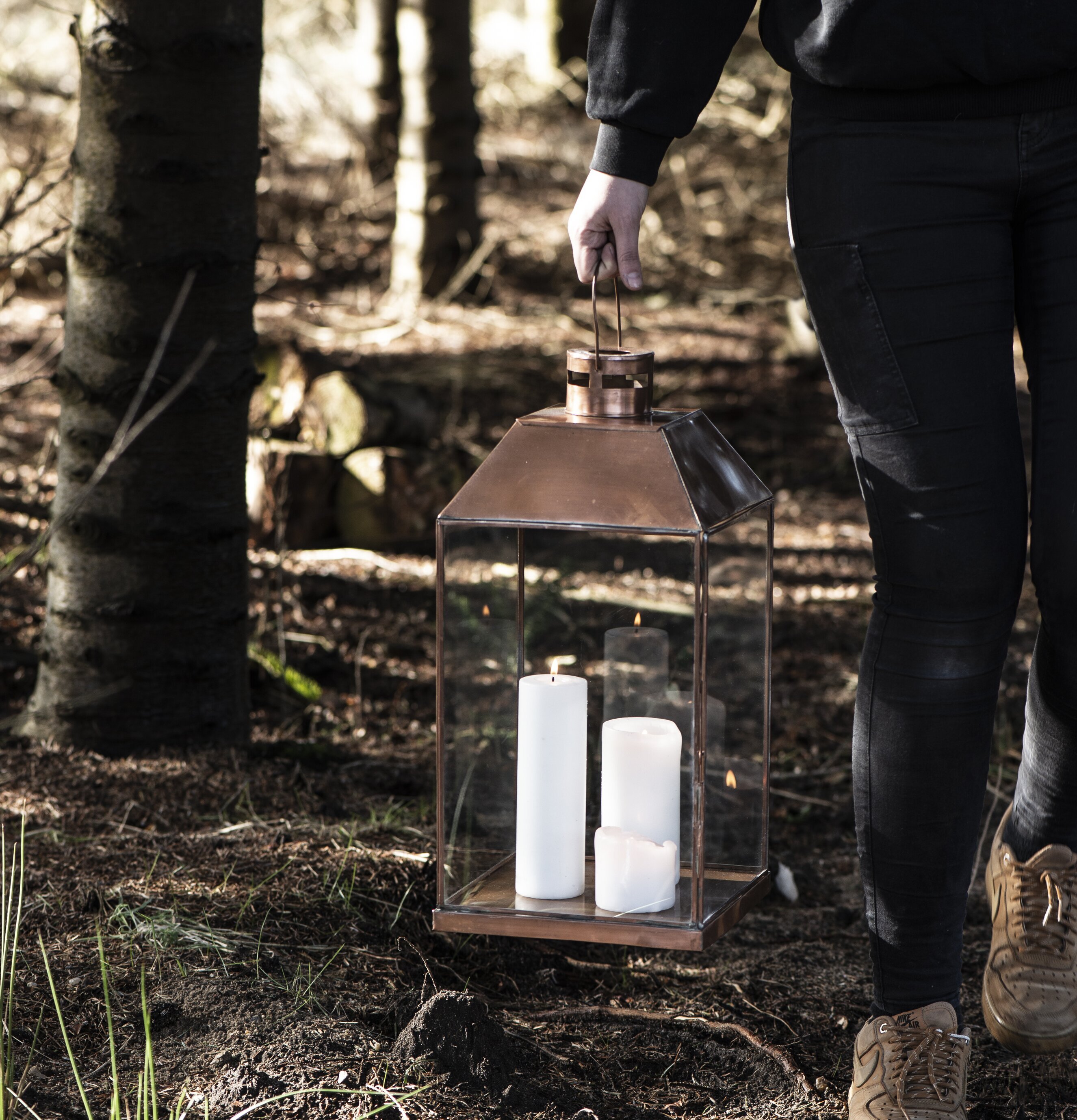 Bild av en person med ljuslykta i skogsmiljö