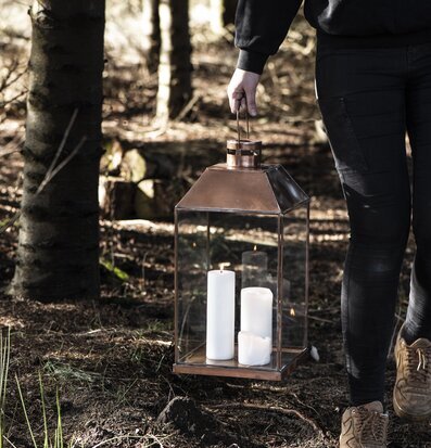 Bild av en person med ljuslykta i skogsmiljö