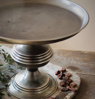 Bild av elegant metallfat på fot i rustik miljö