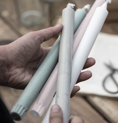 Foto av hand som håller fyra färgglada stearinljus