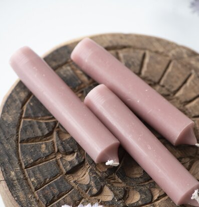 Bild av tre korallrosa stearinljus på trämönstrad yta