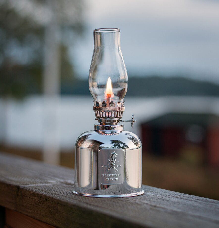 Fotogenlampa Silver från Solstickan på räcke vid sjö