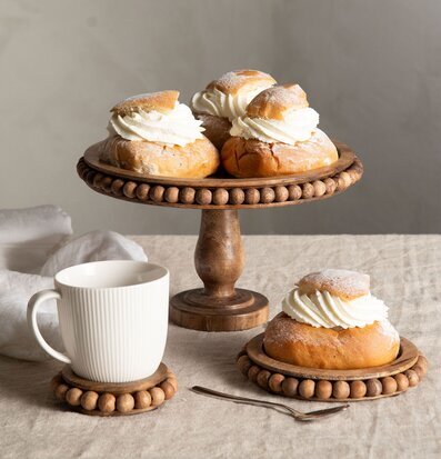 Bild av en inbjudande dukning med träbrickor och semlor