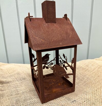 Bild av rostig ljuslykta och fågelmatare i trädgård