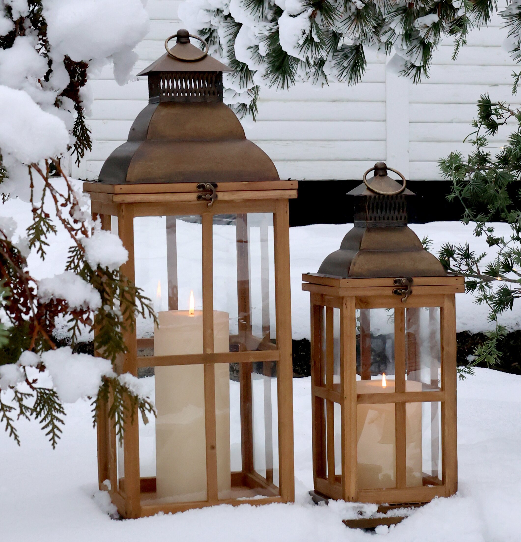 Bild av vinteridyll med ljuslyktor i snöklädd trädgård