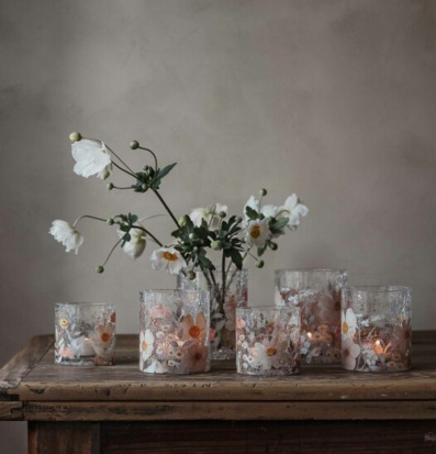 Bild av ljuslyktor och vita blommor på rustikt träbord