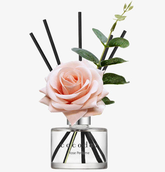 Foto av eleganta doftpinnar med ros och gröna blad