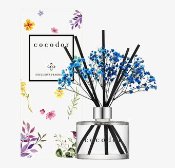 Bild av elegant glasflaska med doftpinnar och blommor