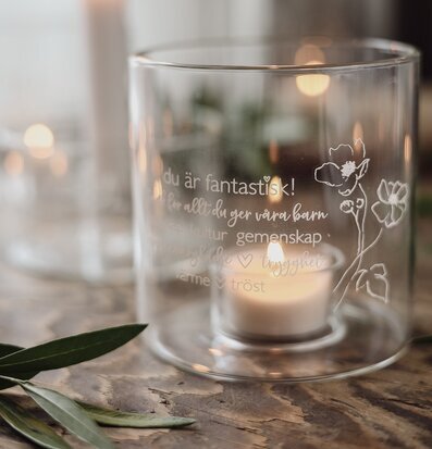 Bild av glaslykta med ingraverad text och blomdetaljer