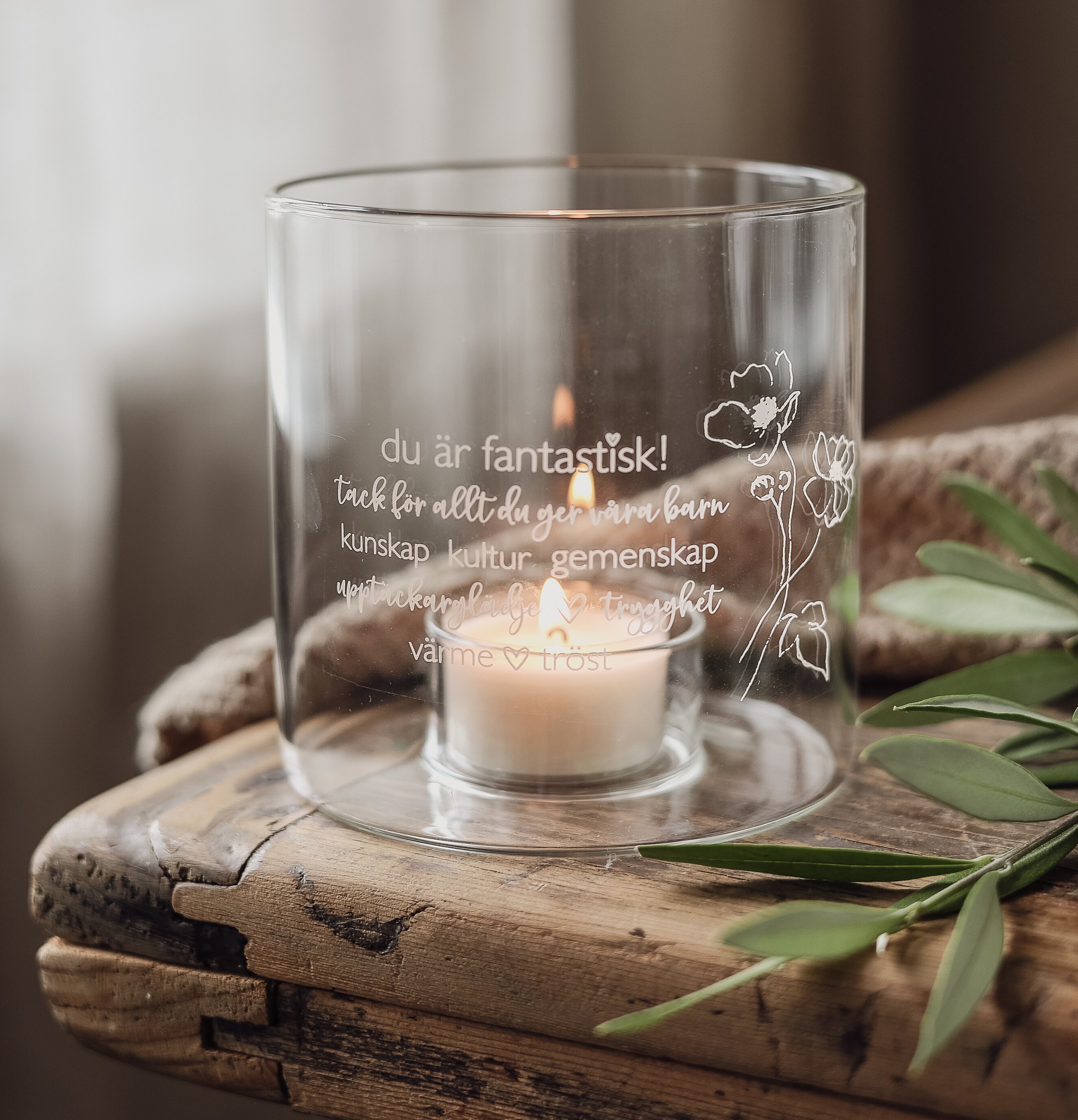 Bild av ljuslykta med blommor och text på rustikt träbord