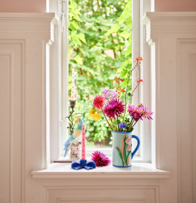 Bild av färgstark ljusstake i ljus fönsternisch med blommor