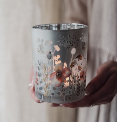 Bild på hand som håller vacker blomstrande ljuslykta med sken