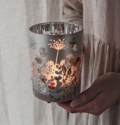 Bild av hand som håller ljuslykta med somrigt blommotiv