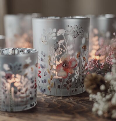 Bild av ljuslyktor med blommönster på träbord i varm miljö