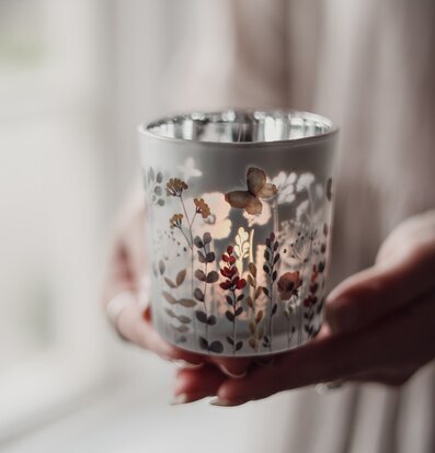 Bild på hand som håller ljuslykta med blommönster och värmeljus