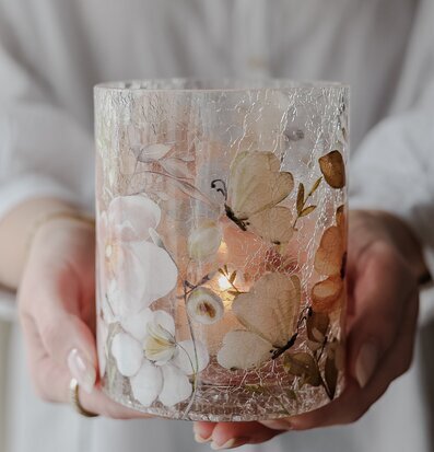 Bild av glaslykta med blommor och fjärilar i sprucket glas