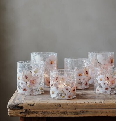 Bild med ljuslyktor i glas på rustikt träbord i mjukt ljus