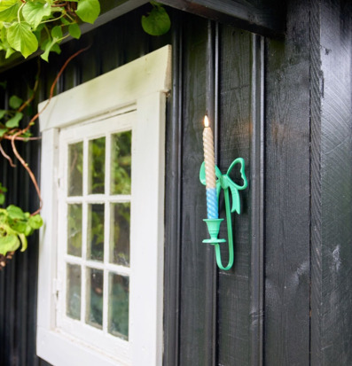 Bild: Utomhus ljusstake i rosett-design på svart träfasad