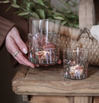 Bild med ljuslyktor och naturmotiv på rustikt träbord