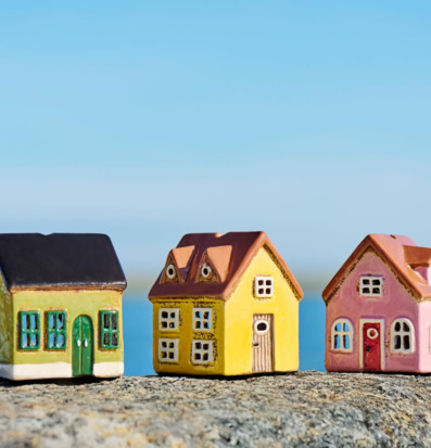 Bild av tre pastellfärgade miniatyrhus-lyktor vid havet