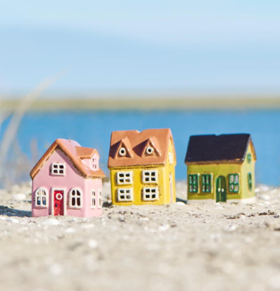 Bild med dekorativa husformade ljuslyktor vid hav i sand