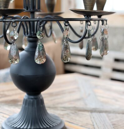 Bild av antiksvart ljusstake med prismor på rustikt träbord