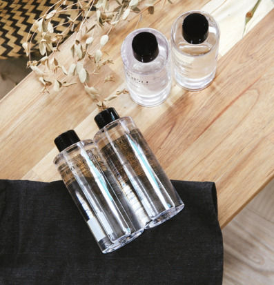 Bild av eleganta refillflaskor på ljust trä med svart tyg