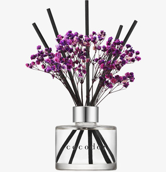 Bild på doftpinnar med lavendel i glasflaska mot vit bakgrund