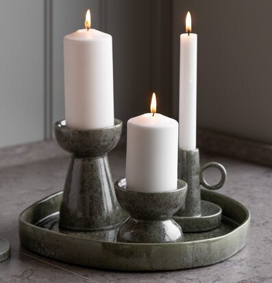 Bild: Gröna keramikljusstakar på fat med tända vita ljus