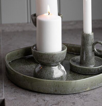 Bild med gröna ljusstakar och levande ljus på keramikfat