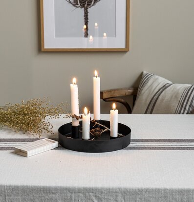 Bild på harmoniskt dukat bord med ljusstake och naturtoner