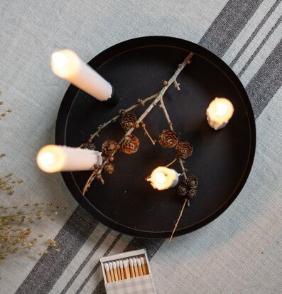 Bild av svart ljusstake med tända ljus och torkade kvistar