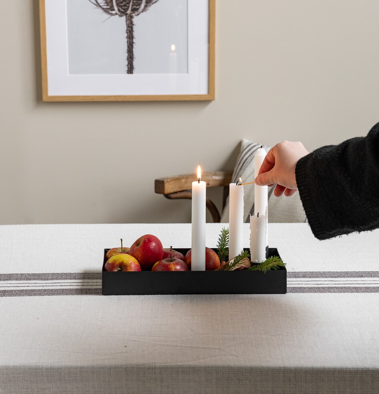 Bild av harmoniskt dukat bord med svart ljusstake och äpplen