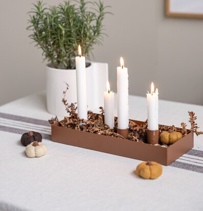 Bild av harmoniskt stilleben med ljusstake, linne och växter