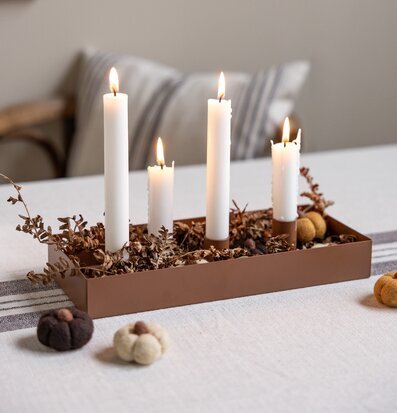 Bild på stilrent dukat bord med brun ljusstake och höstdekor