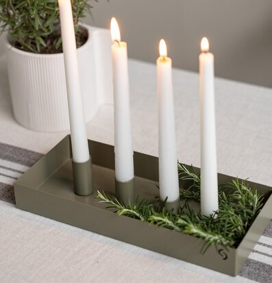 Bild av rektangulär grön ljusstake med tända ljus och örter