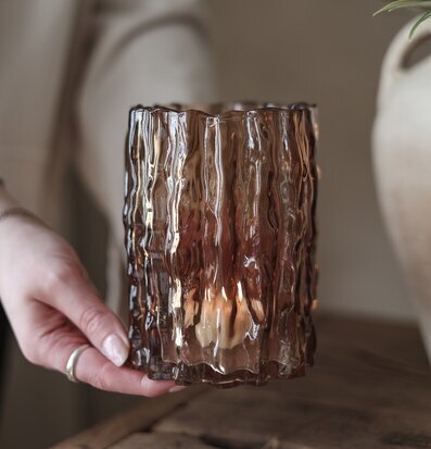 Bild av räfflad brun ljuslykta i glas på rustikt träbord